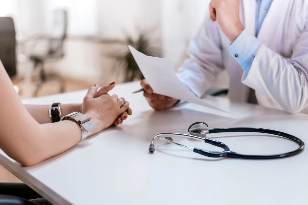 Close-up of a doctor reviewing a document with a patient at a desk.