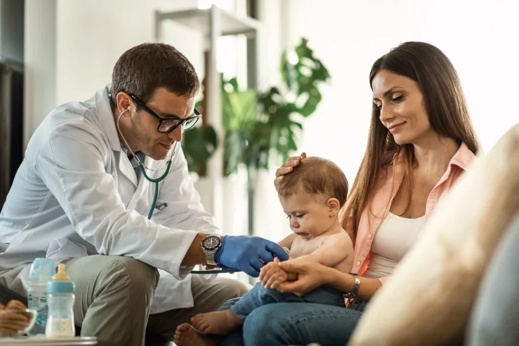 Doctor examining a baby while mother holds & comforts child.