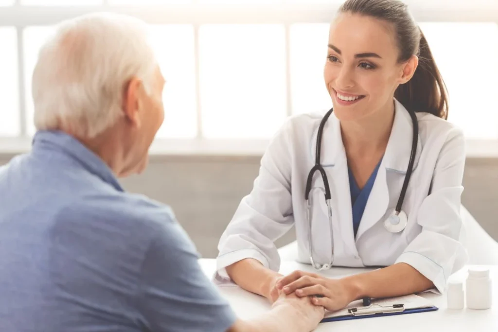Smiling doctor holding an elderly patient's hands during a consultation.
