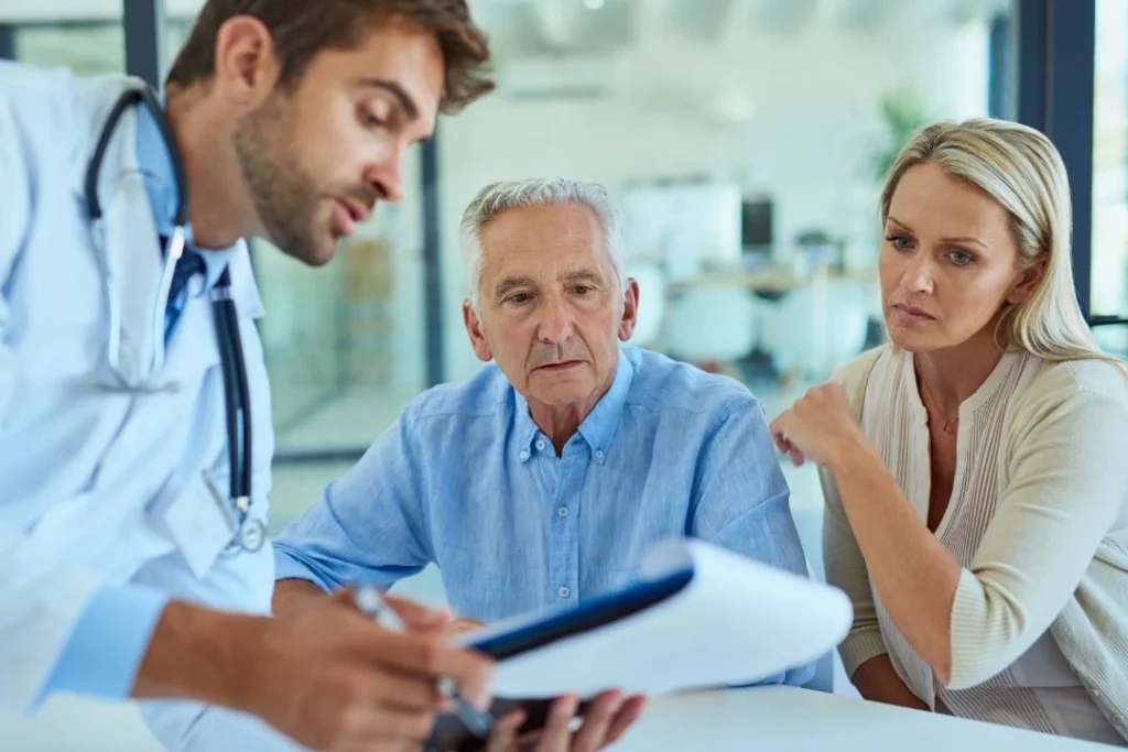 Doctor explaining a document to an elderly man & a woman.