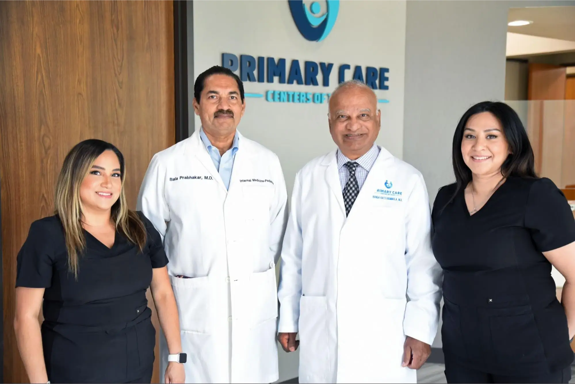 Medical team posing in front of a "Primary Care Centers" sign.