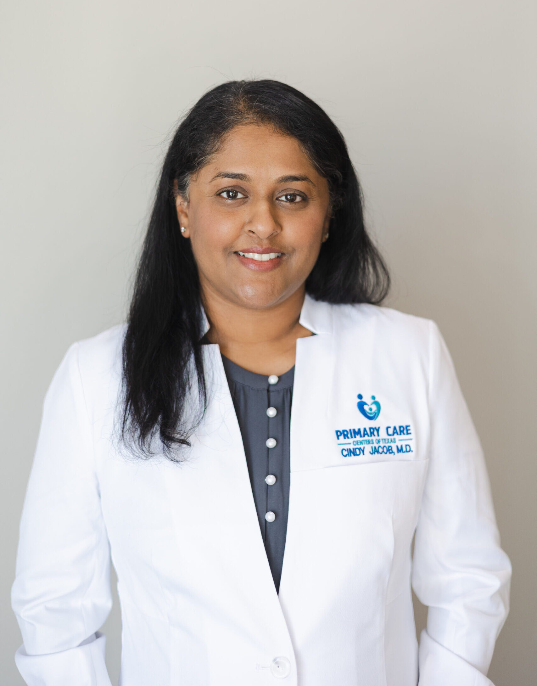 Female doctor wearing white coat, smiling confidently.
