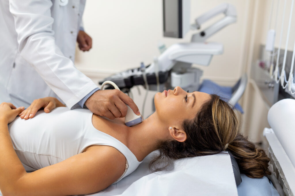 Doctor performing neck ultrasound on patient woman.