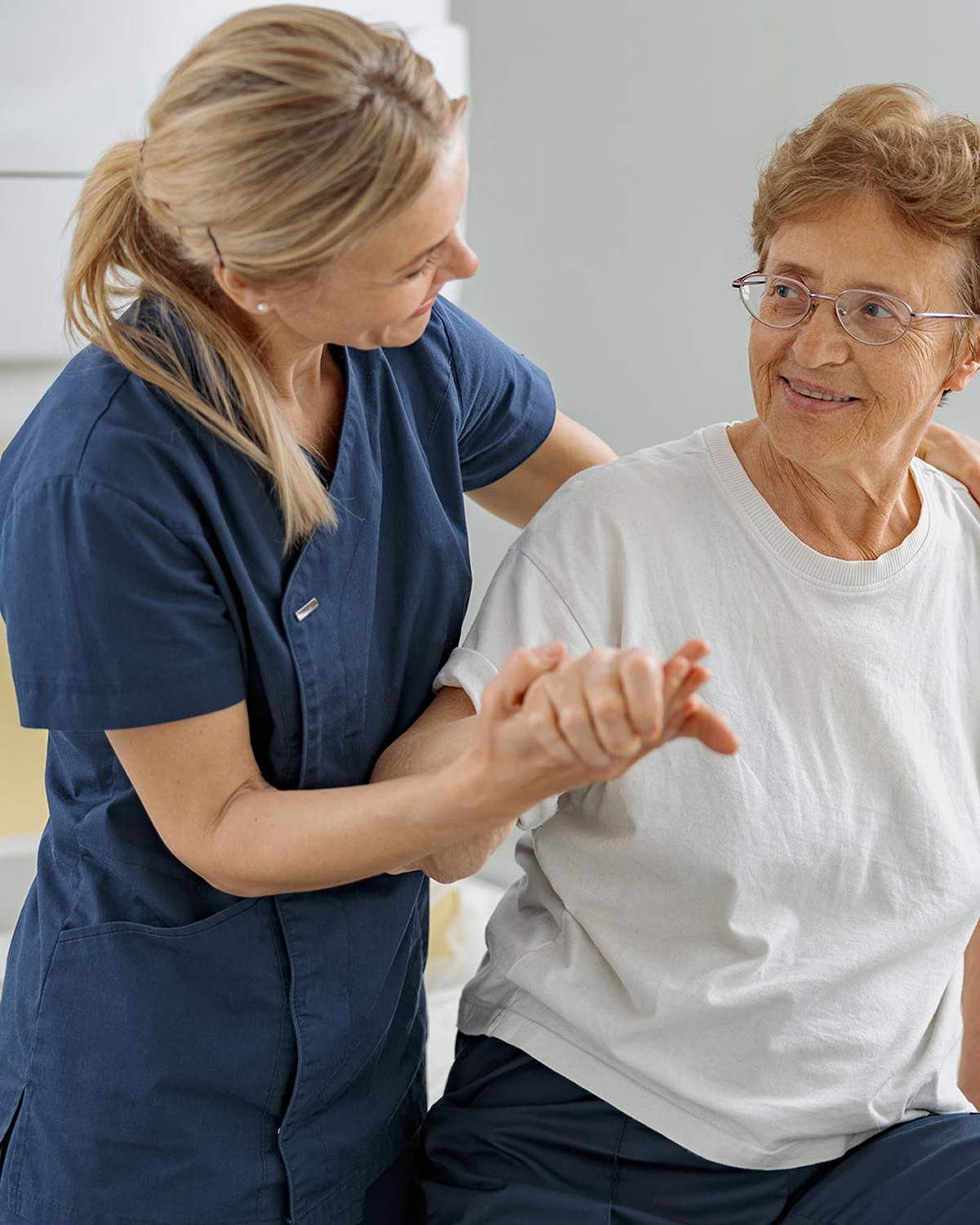 Nurse helping elderly woman with physical therapy.