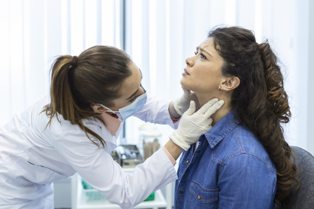 Doctor examining patient's neck in medical office.