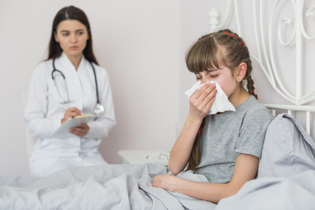 Doctor observing sick girl wiping her nose.