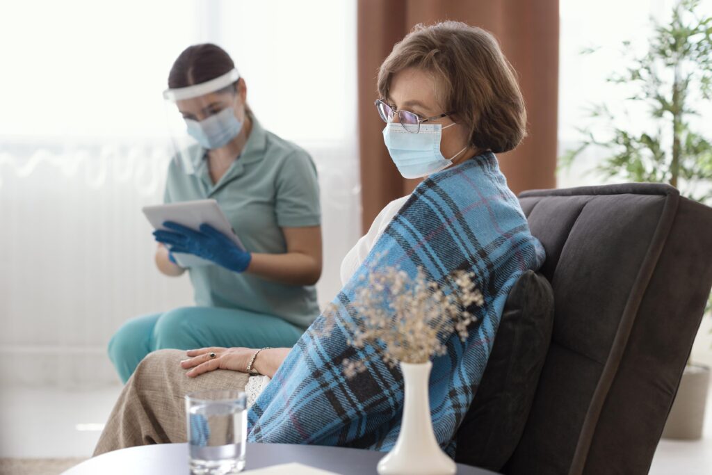 Nurse assisting elderly woman wearing face mask.